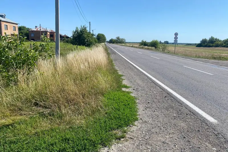 Асфальтована дорога з розміткою по фронту ділянки, електроопора, будинки сусідів